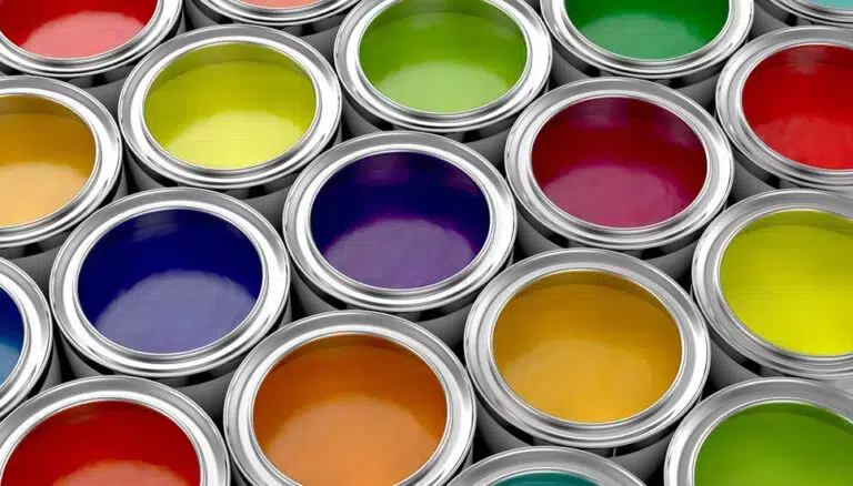Offene Farbdosen sind in Reihen angeordnet und zeigen eine Vielzahl leuchtender Farben, darunter Gelb, Grün, Rot, Blau und Orange. - Farbenhaus Pflüger - Raumausstattung, Bodenbeläge, Vinylboden, Parkett, Farben, Malerarbeiten - Simmenet 2, 37235 Hessisch Lichtenau